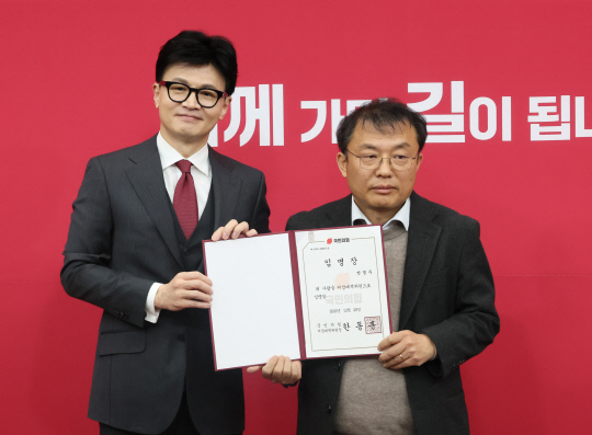 한동훈 국민의힘 비상대책위원장이 지난 12일29일 국회에서 열린 비상대책위원 임명장 수여식에서 '탈(脫) 586 운동권 출신' 민경우 대안연대 공동대표에게 비대위원 임명장을 수여한 뒤 포즈를 취하고 있다. 다만 민경우 신임 비대위원은 그 이튿날(30일) 재야인사 시절 막말 논란이 거듭되자 자진사퇴했다.<연합뉴스 사진>